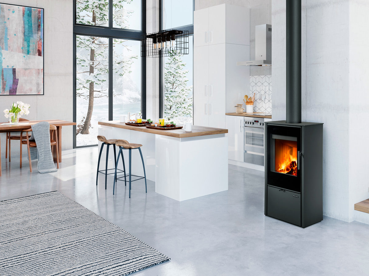 Soba pe lemne moderna din otel Laredo F30 intr-o bucatarie open space luminoasa cu design scandinav, fereastra mare si vedere spre peisaj de iarna cu zapada.