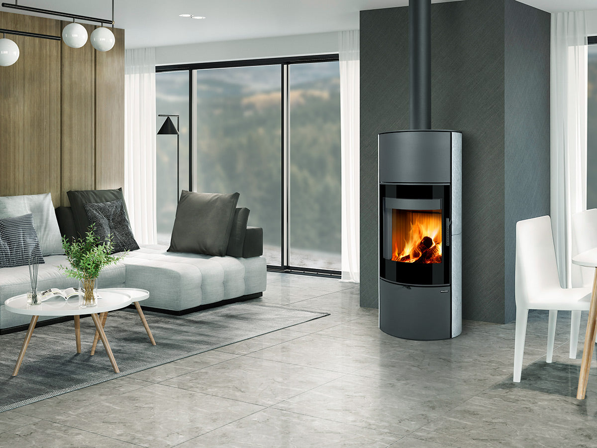 Soba piatra Ovalis G H cu geam frontal mare si foc vizibil, amplasata in living contemporan elegant cu ferestre panoramice si design minimalist.
