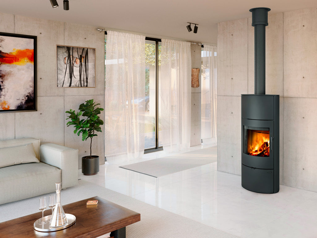 Soba metalica cu acumulare Ovalis H 30 montata intr-un living cu design industrial, pereti cu aspect de beton