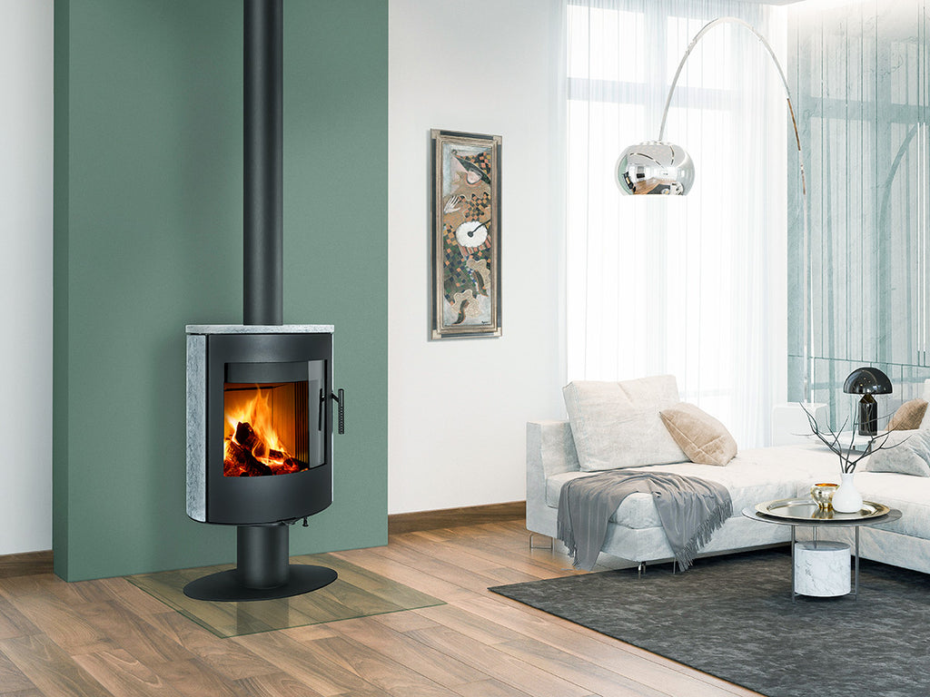 Soba rotativa pe lemne moderna cu picior Ovalis T 22 si imbracaminte din piatra, instalata in living elegant cu perete verde, canapea alba, parchet si decor contemporan.