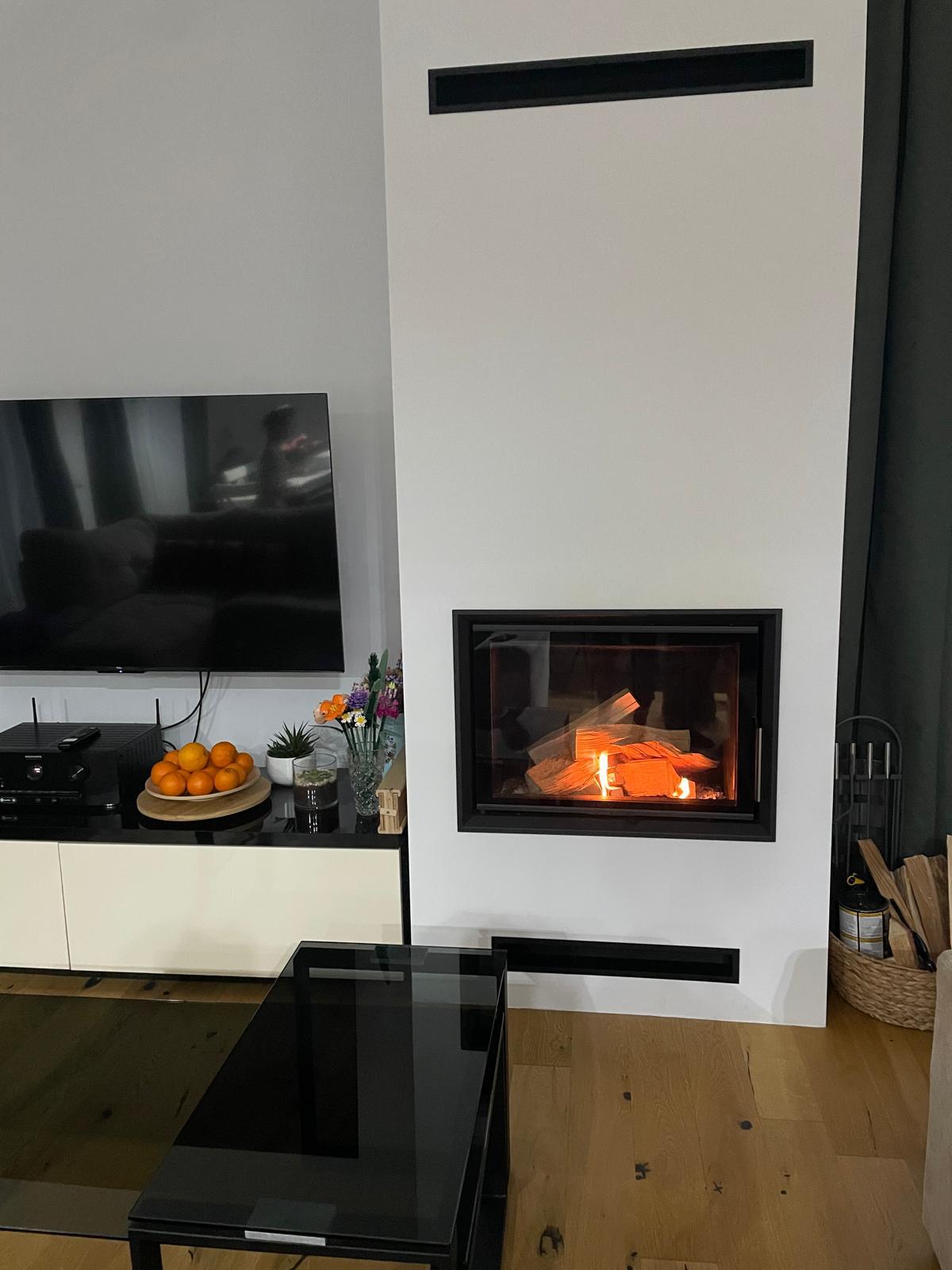 Semineu pe lemne modern, cu geam drept, foc aprins, montat in living langa televizor