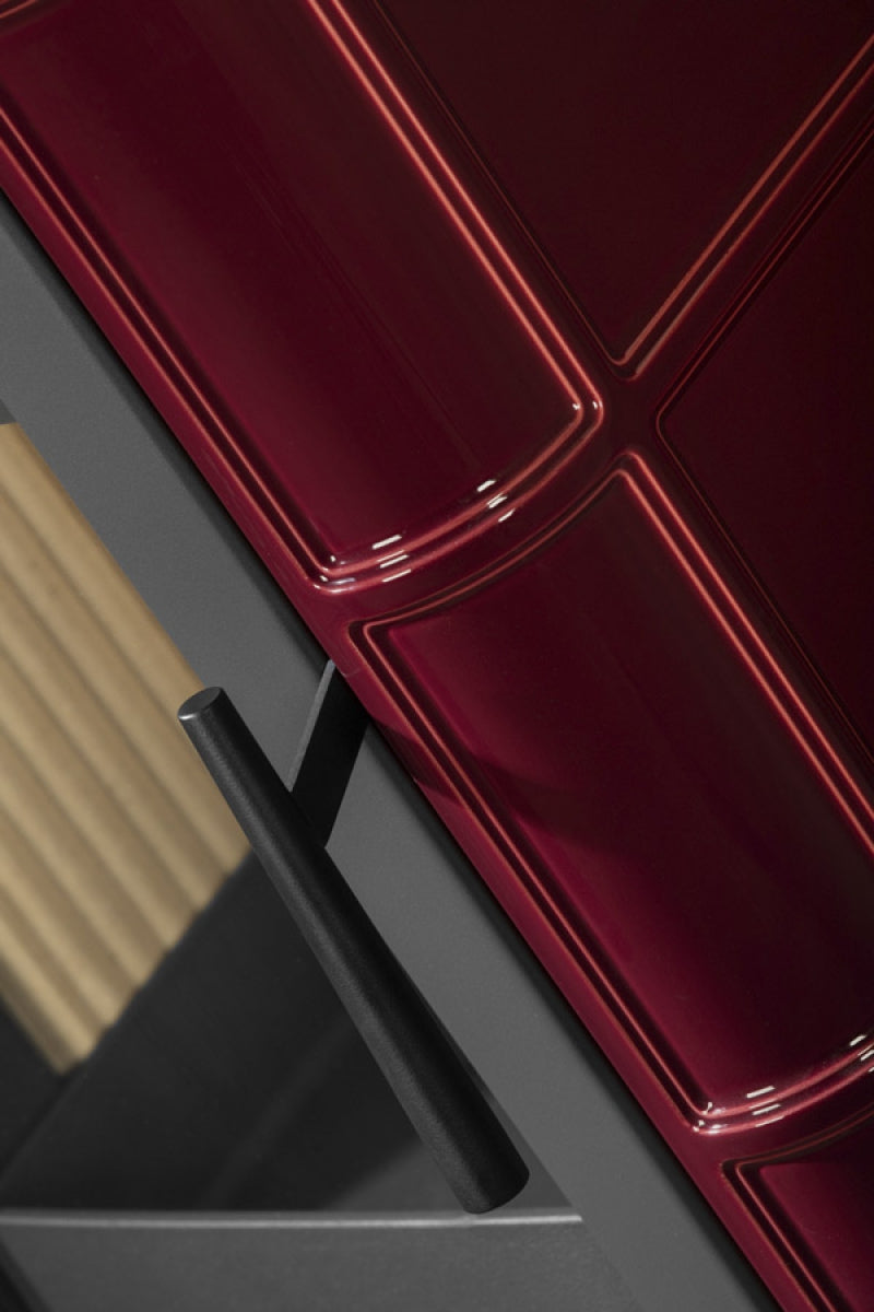 Soba lemne SIENA, usa metalica gri inchis cu placi ceramice lucioase, rosu visiniu, cu model geometric in relief si maner negru. Interior modern.