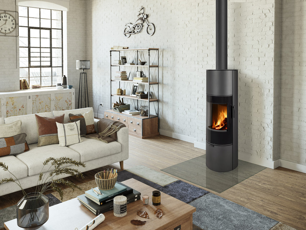 Soba lemne SORIA H 30, cilindrica, din metal negru, cu usa de sticla si foc vizibil. Amplasata intr-un living spatios, stil industrial.